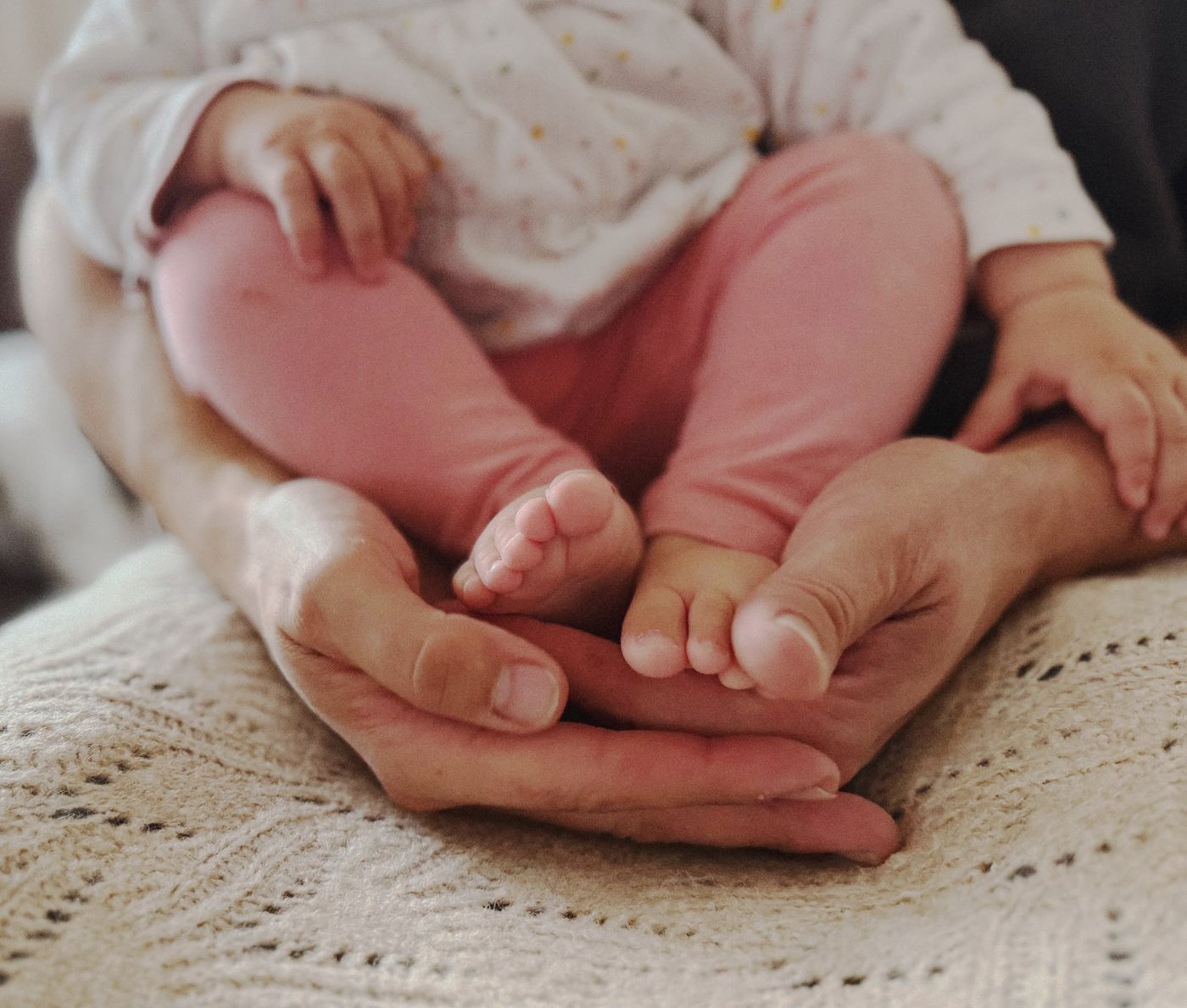 Babyfüße in den Händen der Mama