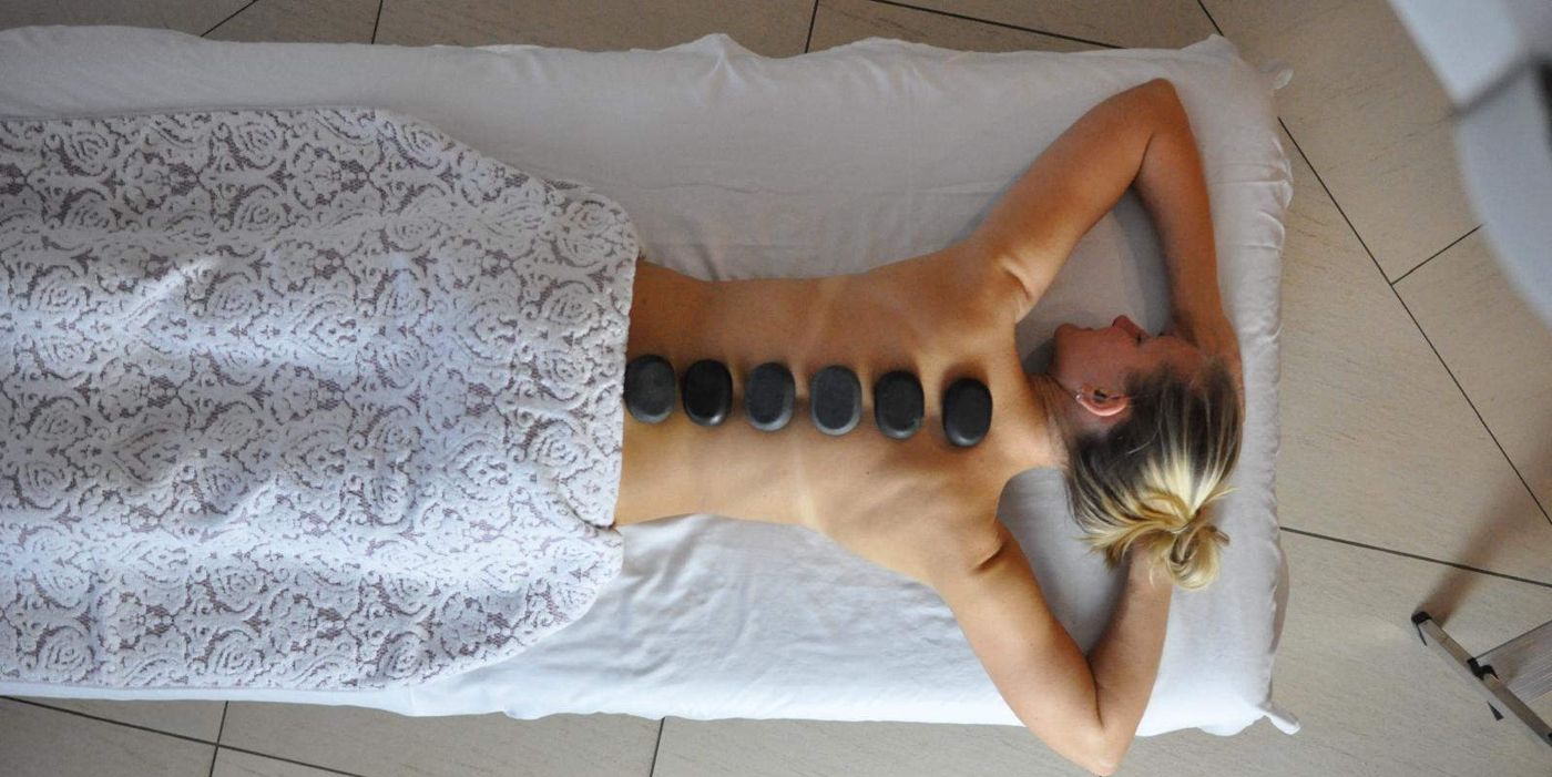 Hot-Stone-Massage mit warmen Steinen auf dem Rücken