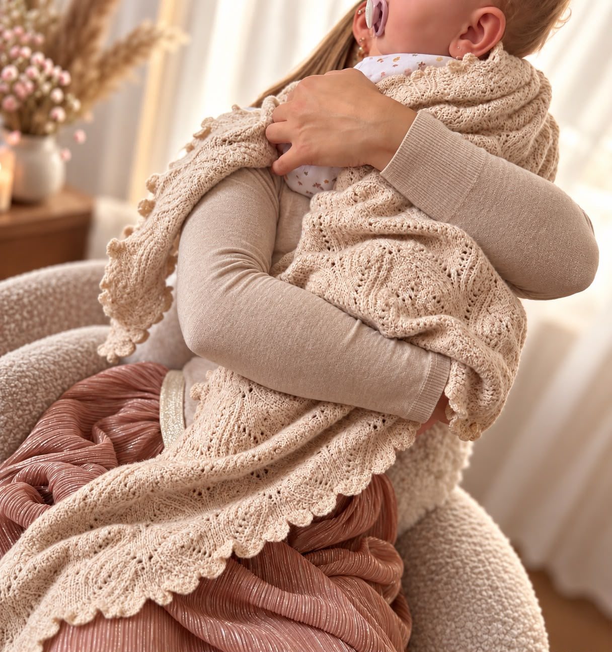Mama hält ihr Baby in einer Strickdecke im Arm